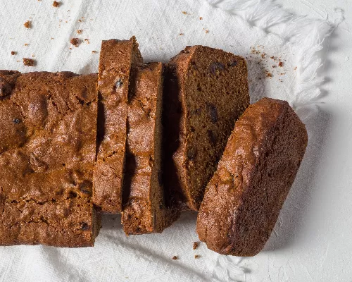 Sliced orange date loaf resting on a tea towel