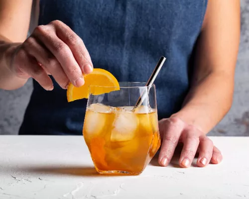 A glass of orange-ginger whisky with orange slices
