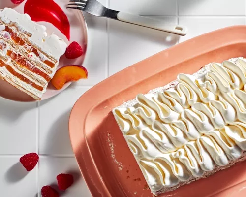 Peach melba icebox cake shown on a peach platter garnished with a peach slice and raspberries