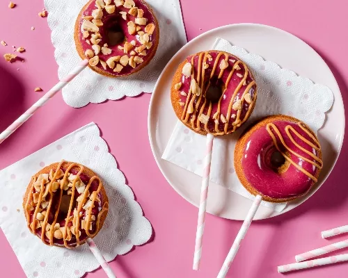 Glazed donuts on sticks with peanut butter drizzle and crushed peanuts