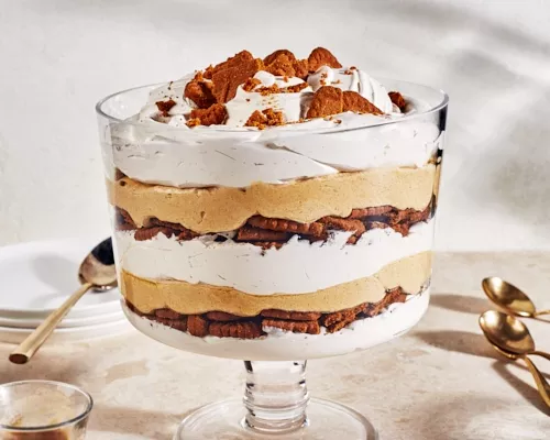 Family-size pumpkin cheesecake trifle in a large, stemmed glass bowl with cookie crumble on top