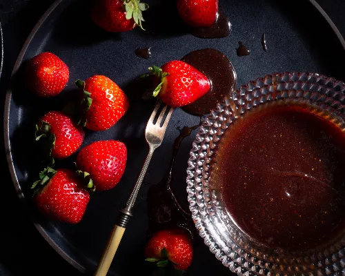 Glass bowl of strawberry-wine caramel sauce with whole strawberries