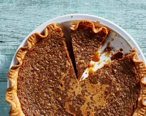 Tarte au Sucre, or sugar pie, in a white pie plate with two slices cut, one missing.