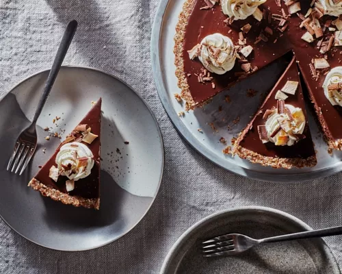 No-bake vegan chai chocolate tart on a platter with two slices cut, one served on a plate