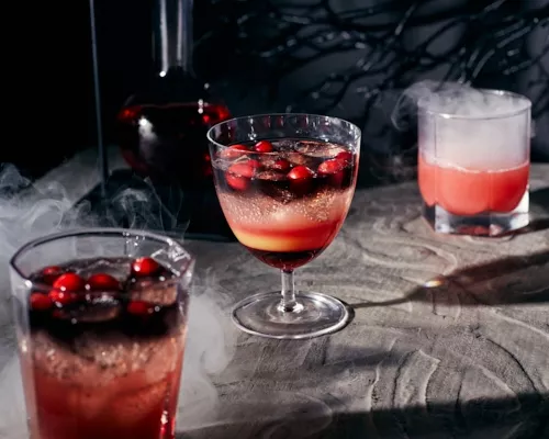 Black vodka and cranberry cocktail on a spooky background with swirling smoke