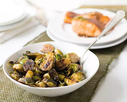 caramelized brussel sprouts in a white bowl with a spoon