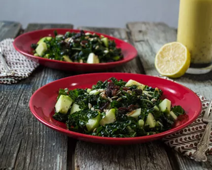 Two red bowls with Apple Kale Salad with Lemon Poppy Seed Vinaigrette