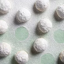 Snowball cookies on a green background, dusted with icing sugar