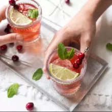 Hands grabbing Cranberry Mint Punch off a silver tray