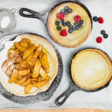 German pancakes in skillets with spiced apples, blueberries and raspberries