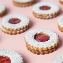Strawberry Linzer Cookies in rows on a pink background
