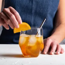 A glass of orange-ginger whisky with orange slices