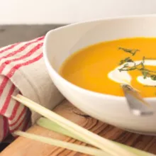 Curried Carrot and Coconut Soup in a white bowl with a spoon and a napkin