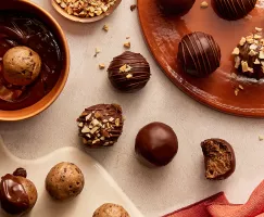 Chocolate-Dipped Cookie Dough Bites in various stages of completion, some sprinkled with nuts, one with a bite missing