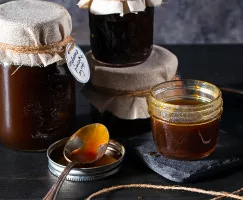 Four jars of molasses pancake syrup, one open with a spoon beside