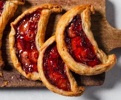 Four strawberry date galette crescents on a wooden cutting board