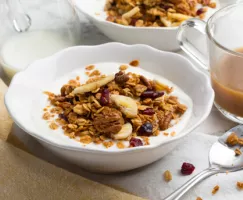 A bowl of yogurt topped with banana and pecan granola