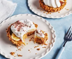pe hero - Two single-serving banoffee pies on white plates, one with a piece removed