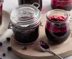 Blueberry jam in a jar and a small vase with a serving spoon