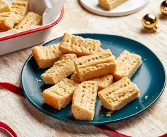 Shortbread cookies on a blue plate with red ribbons and gold Christmas ornaments