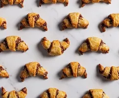 Chocolate tahini rugelach crescents arranged on a marble counter