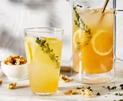 Sparkling chrysanthemum tea lemonade in a glass and a glass pitcher, served with lemon slices and chrysanthemum sprigs and flowe