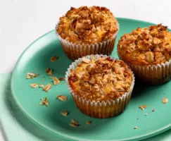 Three muffins topped with coconut streusel on a green plate