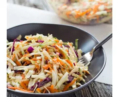 Coleslaw and Cucumber Salad in a black bowl with a fork