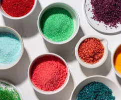 Several bowls of coloured sugar (edible glitter) in different shades and textures