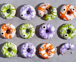 Cinnamon donuts with colourful icing and eyeball candies on a counter