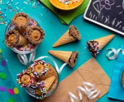 Chocolate dipped ice cream cones full of brown sugar fudge with rainbow sprinkles and party decor