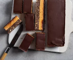 Nanaimo bar cut into slices on a cutting board