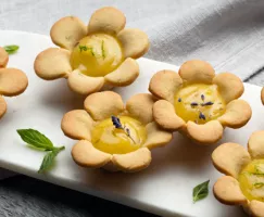 Flower-shaped tart with a lime-lavender curd in the middle decorated with lavender and mint leaves