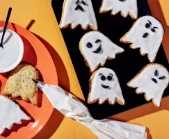 Ghost-shaped tarts, some decorated with black icing faces drawn on white icing, some undecorated