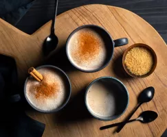 Three mugs of hot horchata garnished with cinnamon sticks and powdered cinnamon