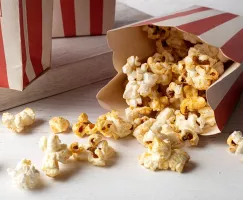 Kettle corn spilling out of a red and white striped popcorn bag