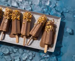 Chocolate Kulfi pops with crushed hazelnuts melting on a tray