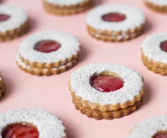 Strawberry Linzer Cookies in rows on a pink background