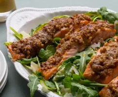 Arugula salad with crusted salmon fillets in a white bowl