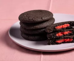 Stacks of dark chocolate cookies stuffed with red marzipan