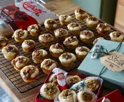 A tray of fruit and nut tarts on grid with cookie boxes