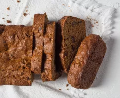 Sliced orange date loaf resting on a tea towel