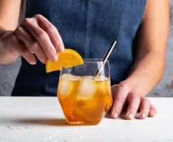 A glass of orange-ginger whisky with orange slices