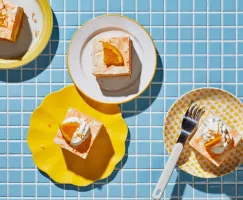 Four pieces of orange vanilla ice cream cake on plates on a blue tiled counter