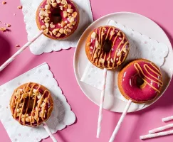 Glazed donuts on sticks with peanut butter drizzle and crushed peanuts