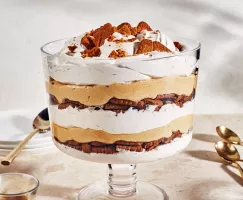 Family-size pumpkin cheesecake trifle in a large, stemmed glass bowl with cookie crumble on top