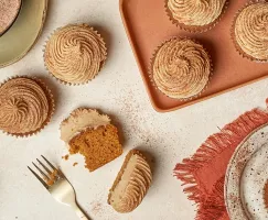  Pumpkin spice cupcakes with frosting, one cut in half, on a table