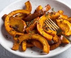 Roasted pumpkin sections in a dish with seasoning