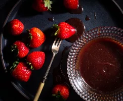 Glass bowl of strawberry-wine caramel sauce with whole strawberries