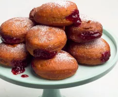A stack of sufganiyot dripping jelly on a cake stand